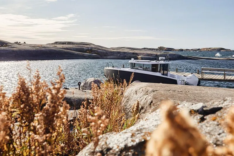 The Image of Coastal scene with 2027 XO EXPLR 9 boat docked by rocky shore. - 0