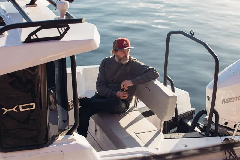 Slide: The Image of Man relaxing on 2027 XO EXPLR 9 boat, holding a drink, near calm water. - 10
