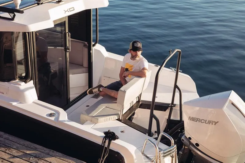 Slide: The Image of Man relaxing on 2027 XO EXPLR 9 boat with Mercury engine by the water. - 11