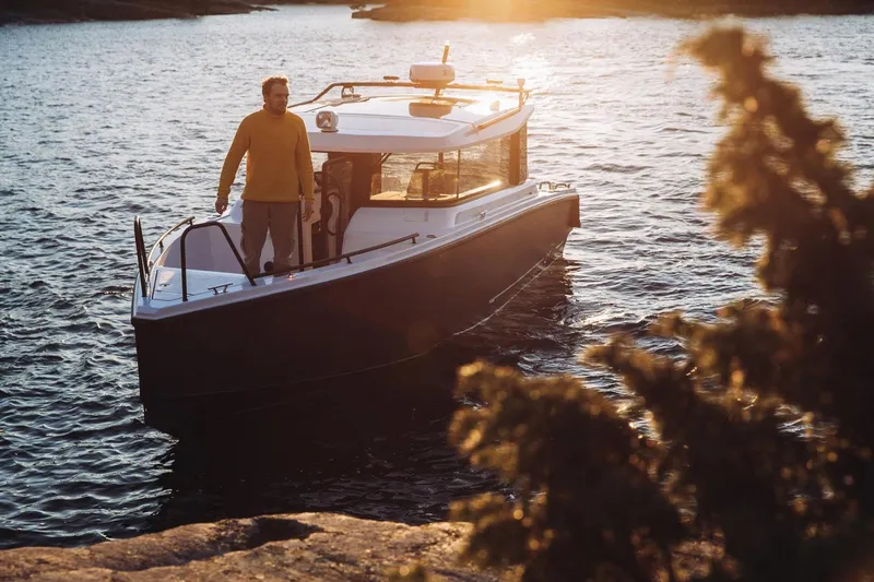 Slide: The Image of Man on XO EXPLR 9 boat at sunset, 2027 model, on calm water. - 13