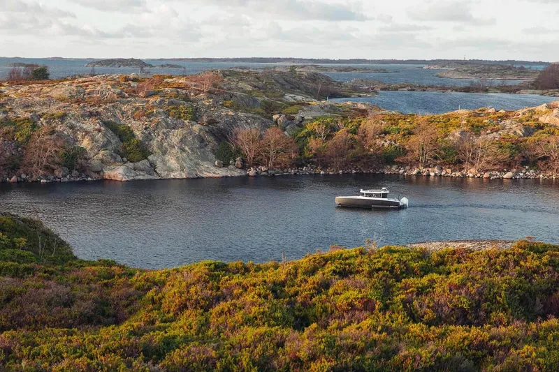 Slide: The Image of XO EXPLR 9 boat navigating serene waters surrounded by rocky landscape, 2027 model. - 5