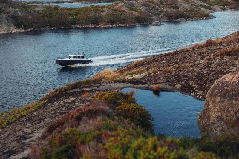 Slide: The Image of 2027 XO EXPLR 9 boat cruising through scenic rocky landscape and calm waters. - 6