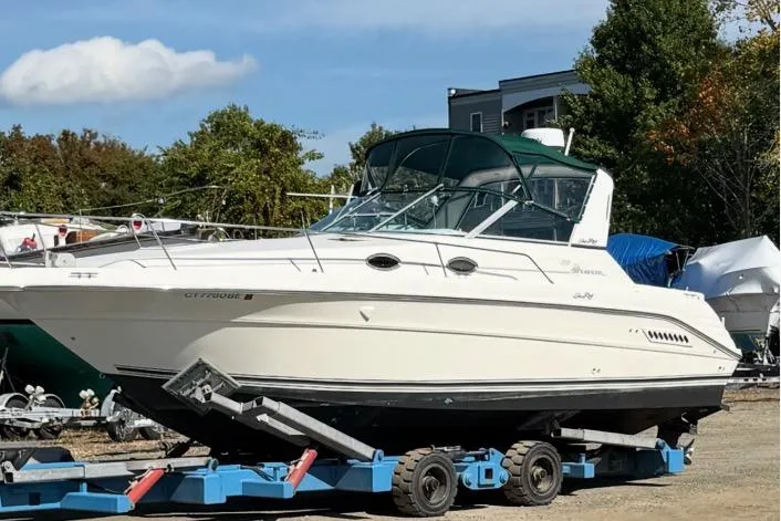The Image of 1994 Sea Ray 300 Sundancer boat on trailer, parked outdoors under clear sky. - 0