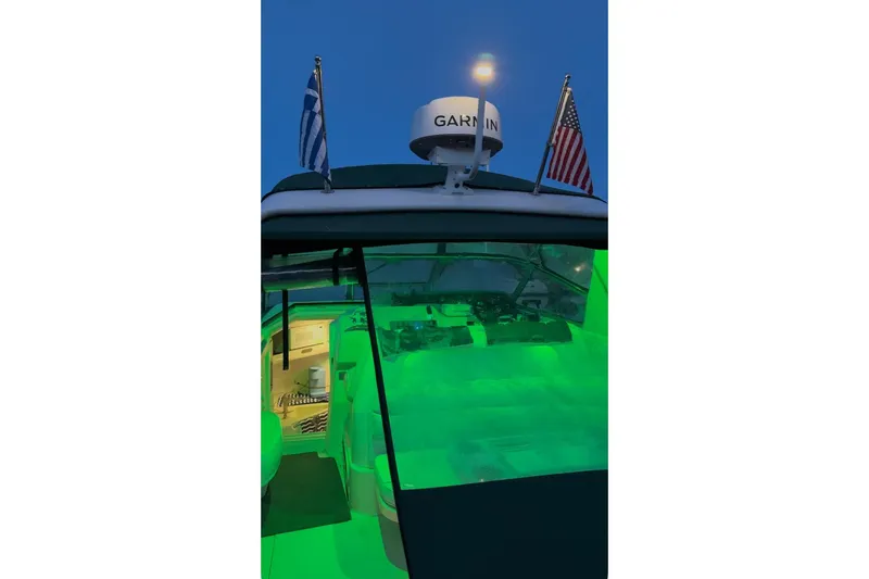 Slide: The Image of 1994 Sea Ray 300 Sundancer with green lighting and flags at dusk. - 11