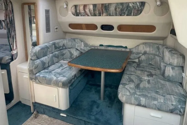 Slide: The Image of Interior of a 1994 Sea Ray 300 Sundancer with cushioned seating and a dining table. - 2