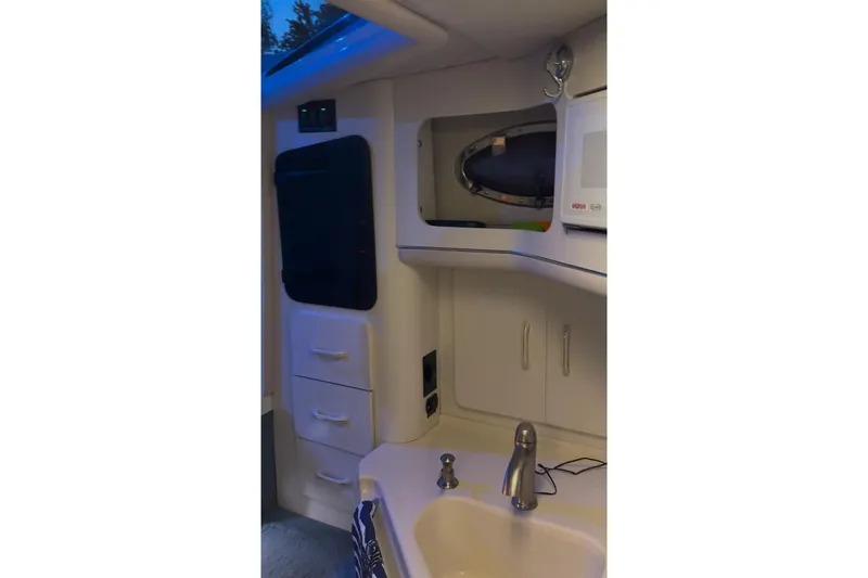 Slide: The Image of Interior of a 1994 Sea Ray 300 Sundancer boat, featuring a compact kitchenette. - 6