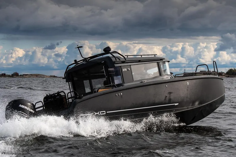 The Image of 2027 XO EXPLR 10 Sport Plus boat navigating choppy waters under cloudy skies. - 2