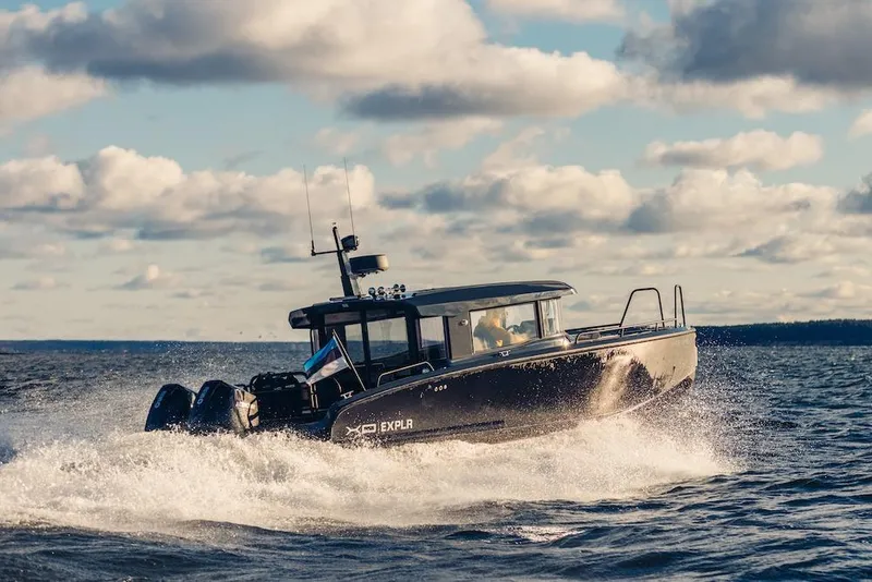 Slide: The Image of 2027 XO EXPLR 10 Sport Plus boat cruising on open water under cloudy sky. - 6