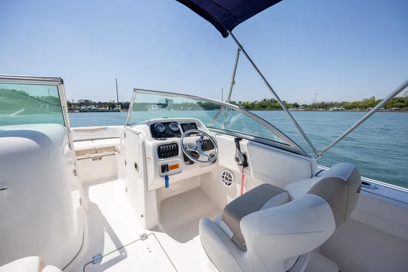 Slide: The Image of 2024 Robalo R207 Dual Console boat interior with steering wheel and seating, on calm water. - 15