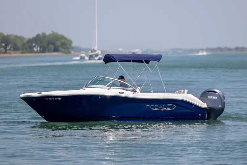 Slide: The Image of 2024 Robalo R207 Dual Console boat cruising on a calm lake with a Yamaha engine. - 9