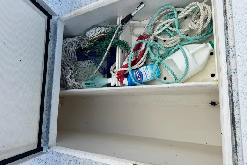 Slide: The Image of Boat storage compartment with ropes, cleaning supplies, and netting on a 2008 Force Marine Force 21. - 11