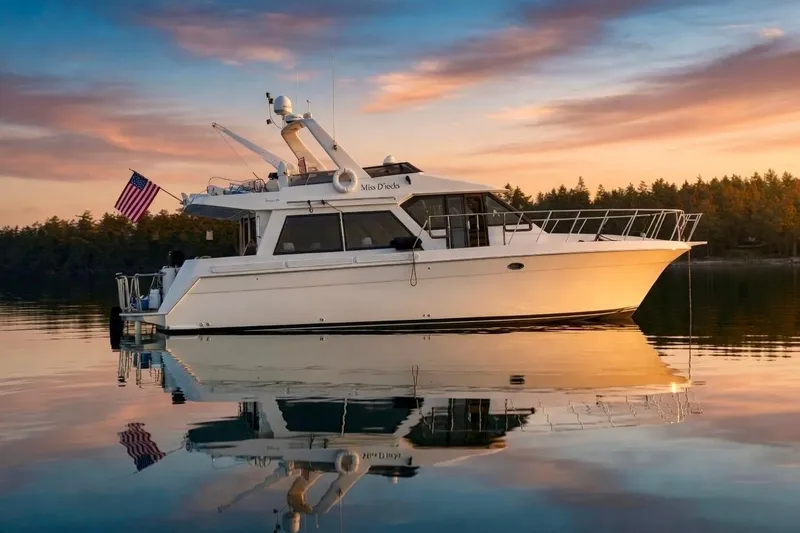 The Image of Navigator Classic 1994 yacht on serene water at sunset with forest backdrop. - 0
