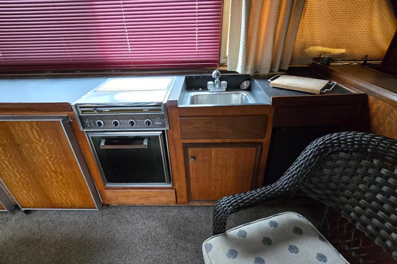 Slide: The Image of 1975 Hatteras 46 Convertible yacht kitchen with stove, sink, and wicker chair. - 10