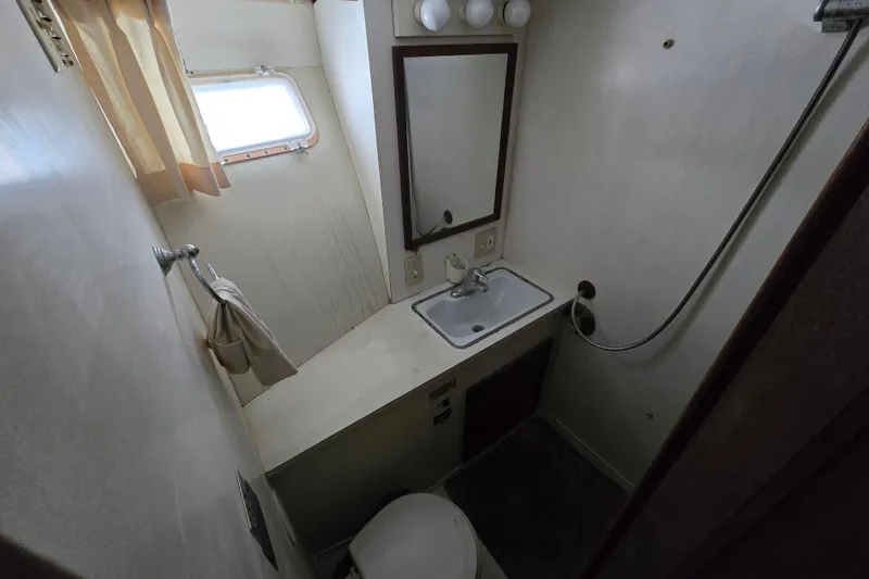 Slide: The Image of 1975 Hatteras 46 Convertible bathroom with sink, mirror, and porthole window. - 24