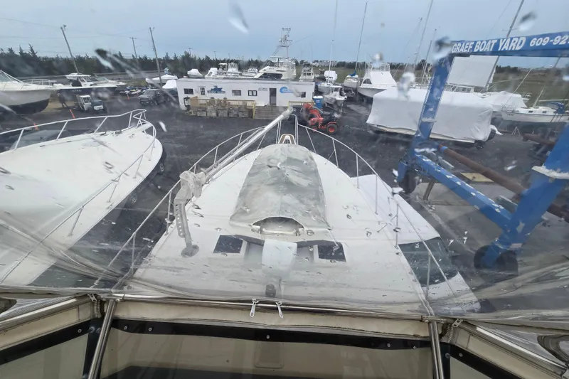 Slide: The Image of 1975 Hatteras 46 Convertible yacht in boatyard, rainy day, surrounded by other vessels. - 29