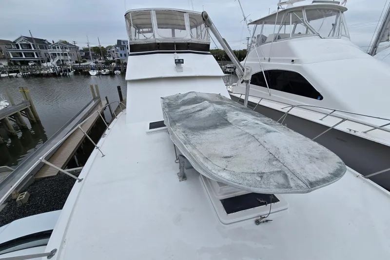 Slide: The Image of 1975 Hatteras 46 Convertible yacht docked, featuring spacious deck and covered equipment. - 30