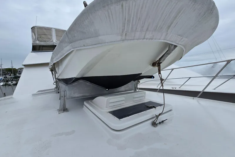 Slide: The Image of 1975 Hatteras 46 Convertible yacht with dinghy on deck, marina background. - 31