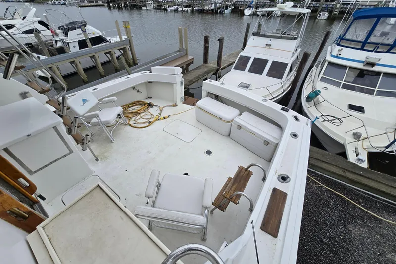 Slide: The Image of 1975 Hatteras 46 Convertible boat docked at marina, featuring spacious deck area. - 32