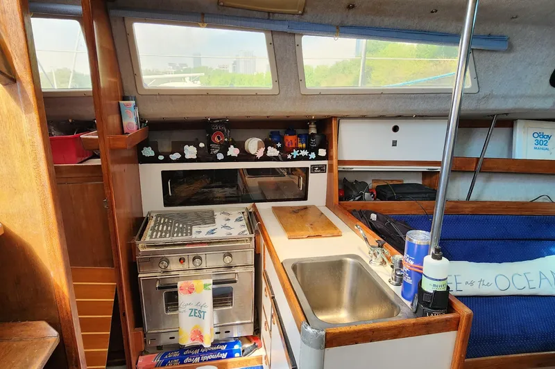 Slide: The Image of Interior of a 1988 O'Day 302 sailboat featuring a compact kitchen area. - 21