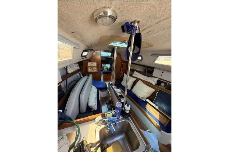 Slide: The Image of Interior of a 1988 O'Day 302 sailboat, featuring cozy seating and a compact kitchen area. - 25