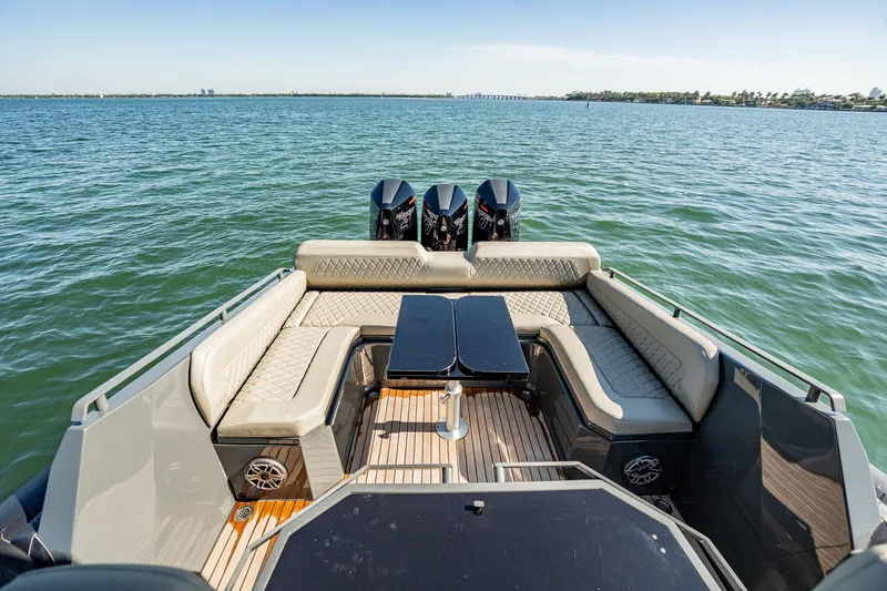 Slide: The Image of Luxurious 2023 Skipper-BSK 38NC boat with plush seating and triple outboard engines on open water. - 103