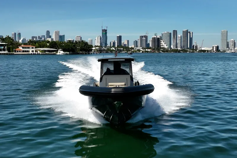 Slide: The Image of Skipper-BSK 38NC boat cruising on water with city skyline in background, 2023 model. - 16