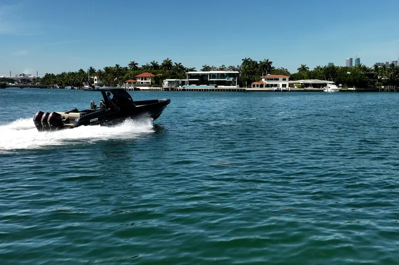Slide: The Image of 2023 Skipper-BSK 38NC speedboat cruising on a sunny waterfront with palm trees. - 22