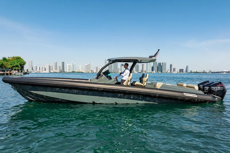 Slide: The Image of 2023 Skipper-BSK 38NC boat cruising on water with city skyline in background. - 53