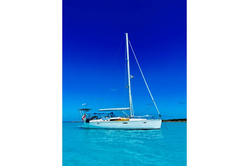 Slide: The Image of Sailboat Beneteau Oceanis 46, 2010 model, anchored in clear blue waters under a vibrant sky. - 2