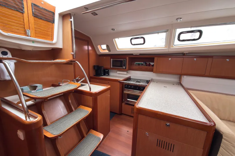 Slide: The Image of Interior of 2010 Beneteau Oceanis 46 yacht, featuring a modern kitchen and wooden cabinetry. - 24
