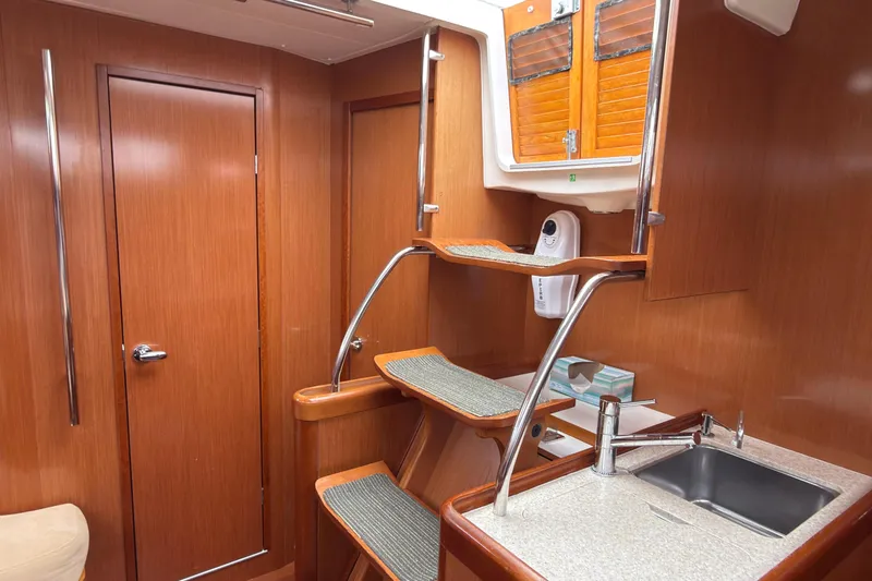 Slide: The Image of Interior of 2010 Beneteau Oceanis 46 yacht with wooden cabinetry and compact kitchen area. - 26