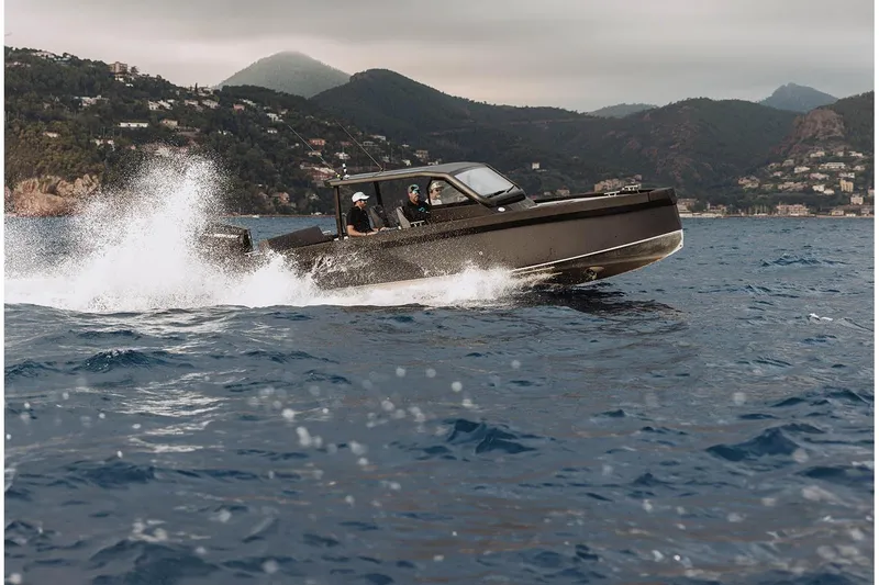 Slide: The Image of XO DFNDR A8 boat cruising on open water, 2027 model, with scenic coastal backdrop. - 14