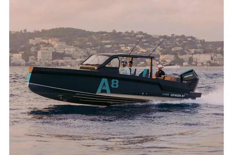 Slide: The Image of 2027 XO DFNDR A8 boat cruising on water near coastal cityscape. - 15