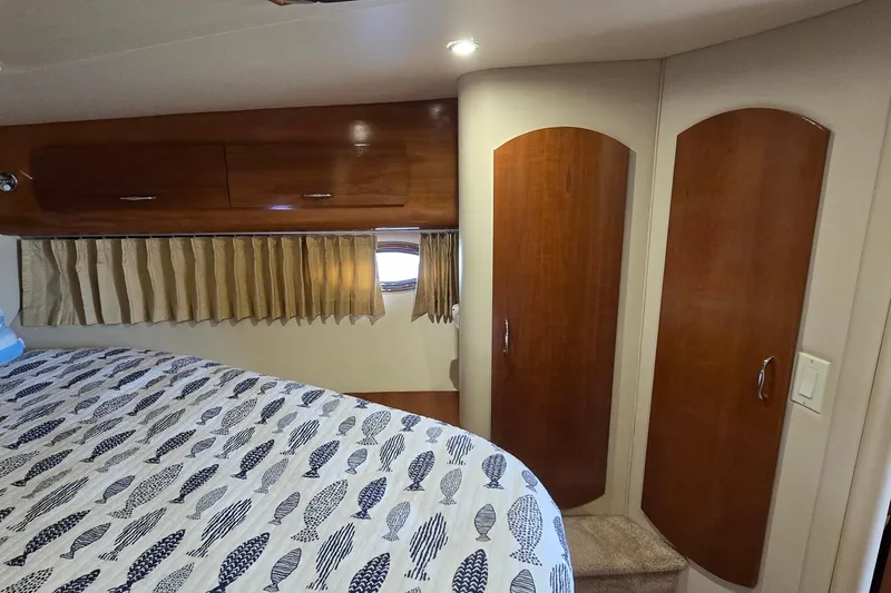 Slide: The Image of Interior of 2006 Carver 36 Mariner with wood cabinets and fish-patterned bedding. - 37