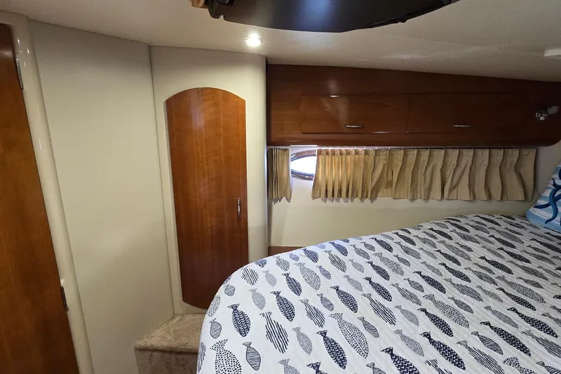 Slide: The Image of Interior of 2006 Carver 36 Mariner yacht bedroom with wood cabinetry and fish-patterned bedding. - 38