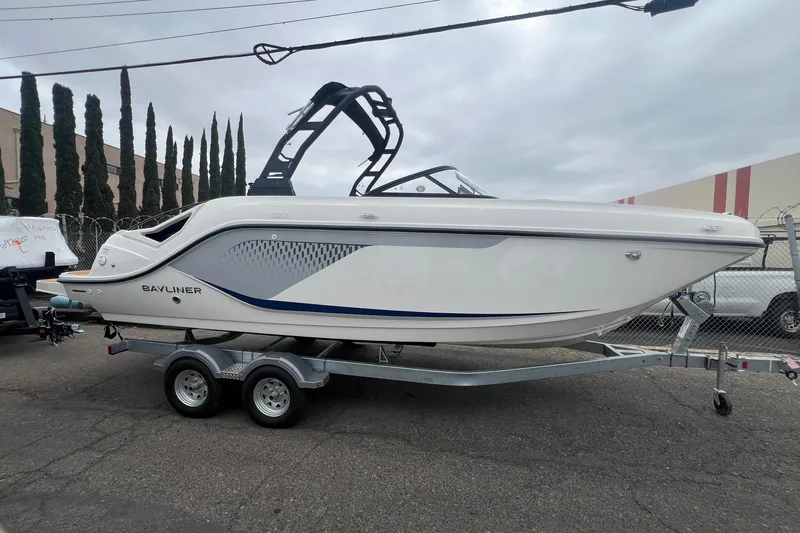 The Image of 2026 Bayliner D22I boat on trailer, sleek white design with blue accents, parked outdoors. - 0