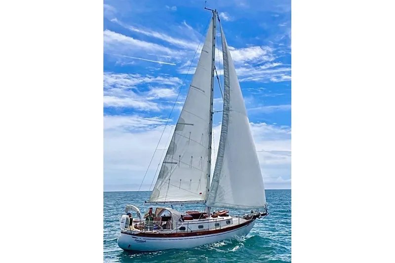 The Image of Vintage 1979 Baba 30 sailboat cruising on open sea under clear blue sky. - 0