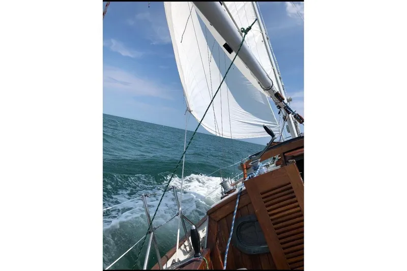 Slide: The Image of Sailing on a 1979 Baba 30 yacht with white sails over blue ocean. - 6