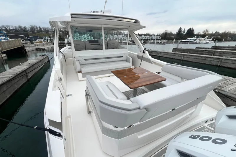 Slide: The Image of 2023 Tiara Yachts 43 LS luxury boat with elegant seating and wooden table in marina. - 10
