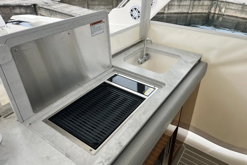 Slide: The Image of Outdoor kitchen area on 2023 Tiara Yachts 43 LS, featuring a grill and sink. - 19