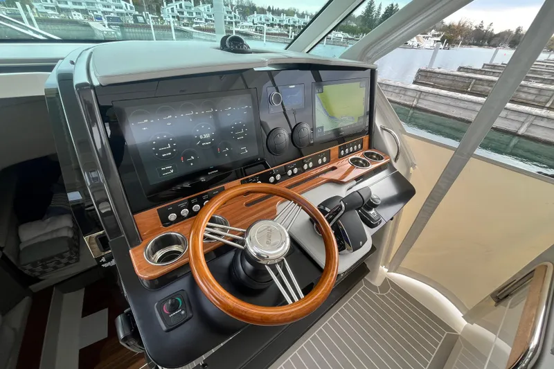 Slide: The Image of Helm of 2023 Tiara Yachts 43 LS with advanced navigation displays and wooden steering wheel. - 23