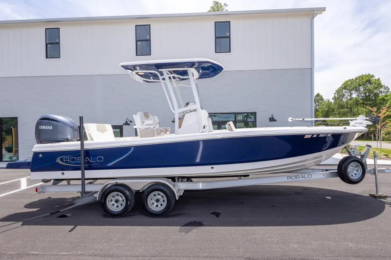 Slide: The Image of 2024 Robalo 246 Cayman boat on trailer, blue and white design, parked outdoors. - 3