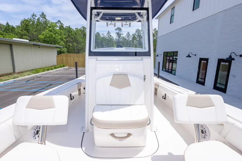 Slide: The Image of 2024 Robalo 246 Cayman boat interior with white seating and console, parked outdoors. - 36