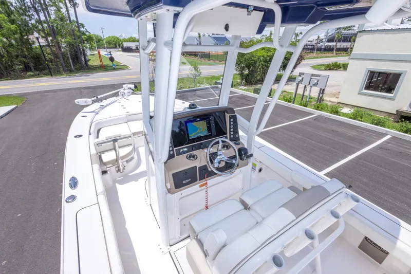 Slide: The Image of 2024 Robalo 246 Cayman boat interior with modern helm and seating in a parking lot. - 42