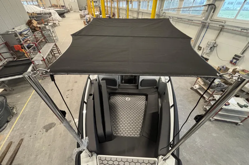 Slide: The Image of 2026 XO DFNDR 8 boat interior with canopy in a workshop setting. - 10