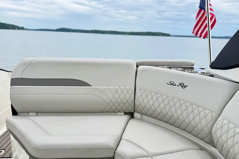 Slide: The Image of Luxurious seating on 2023 Sea Ray SLX 260 boat with American flag, overlooking serene water. - 24