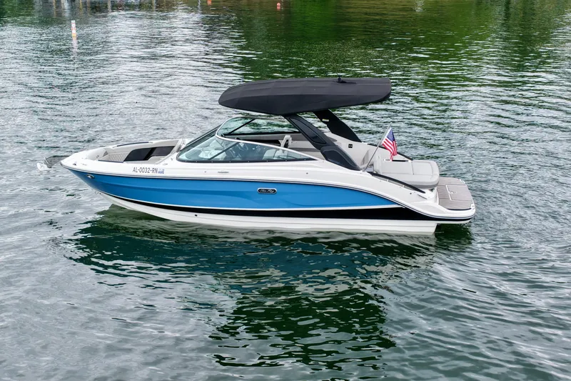 Slide: The Image of 2023 Sea Ray SLX 260 boat with blue hull and black canopy on calm water. - 29