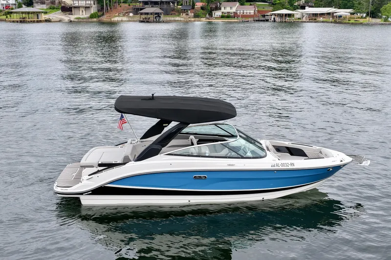 Slide: The Image of 2023 Sea Ray SLX 260 boat on calm lake with shoreline houses in background. - 5