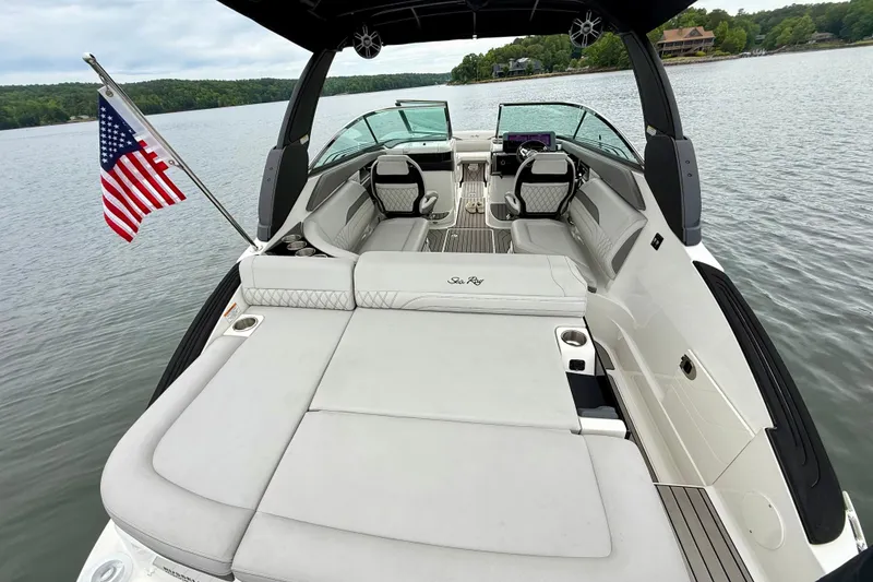 Slide: The Image of 2023 Sea Ray SLX 260 boat with spacious seating, American flag, and scenic lake view. - 7