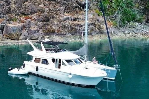 The Image of 2005 Navigator 48 yacht anchored in serene, clear waters near rocky shoreline. - 2